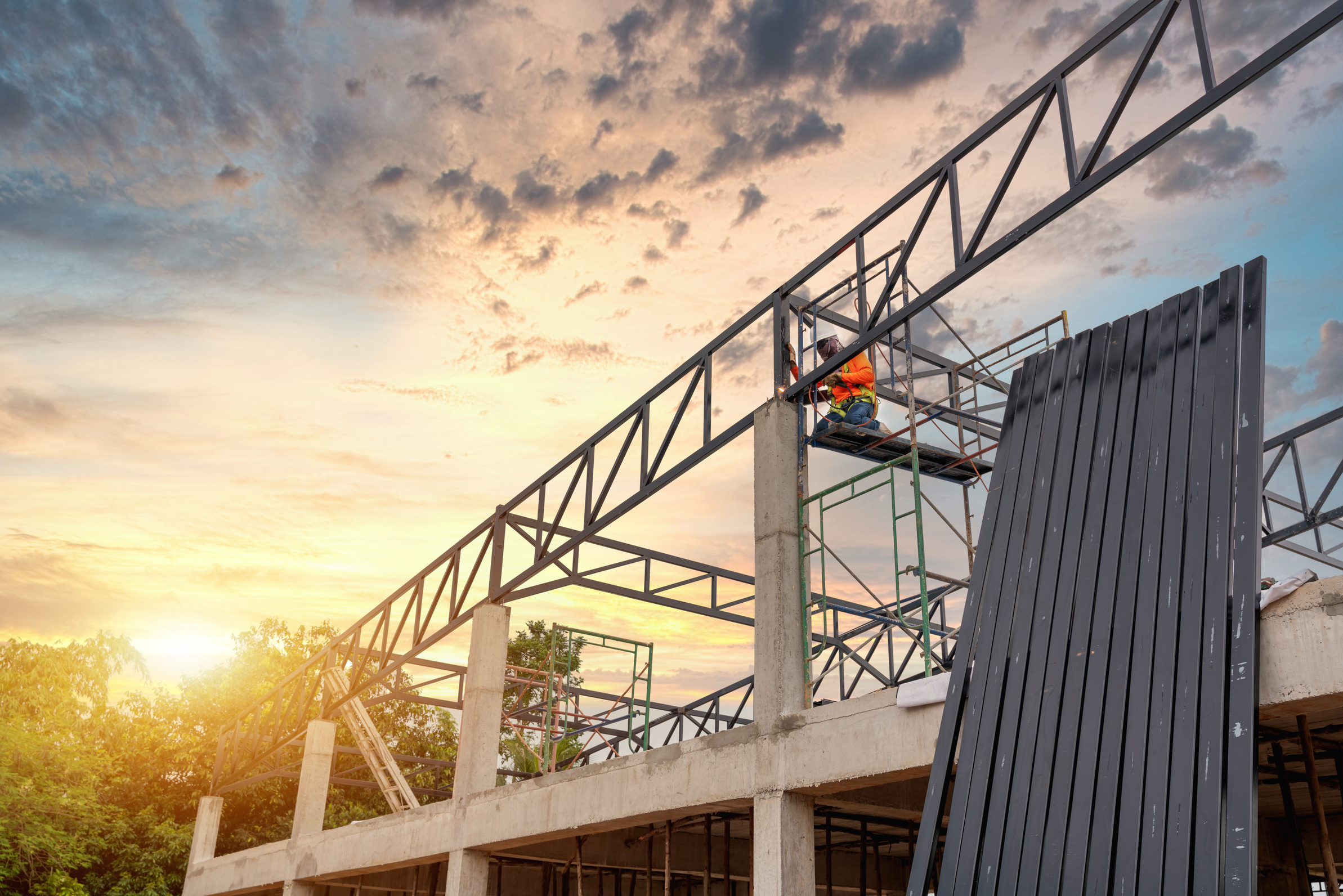 Steel roof truss welders are working on the roof structure with